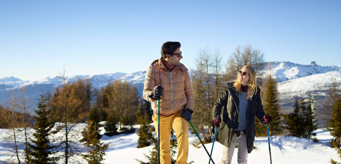 Club Med Peisey - Vallandry, en France - Un couple pratique un sport d'hiver, dans la forêt environnante du Village