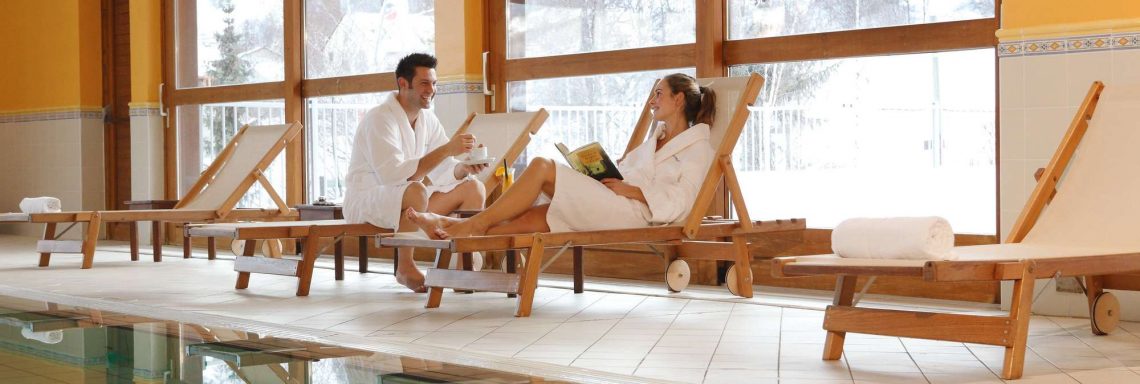 Club Med Serre-Chevalier, en France - Image d'un couple au bord de la piscine intérieure avec vue sur la montagne enneigée