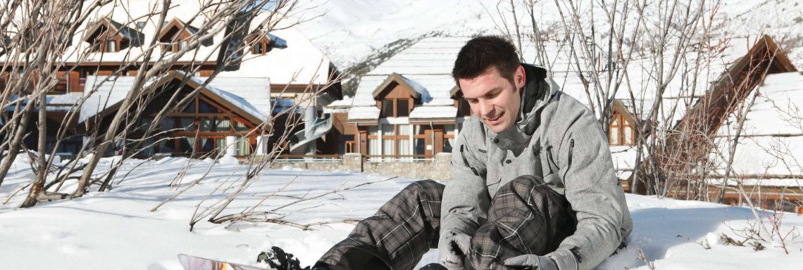 Club Med Serre-Chevalier, en France - Image d'un homme assis dans la neige avec une planche de snowboard