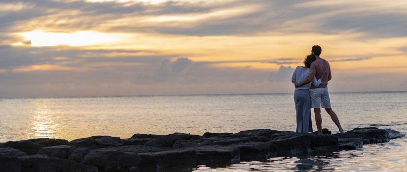 Couple sur une jetée regardant un coucher de soleil