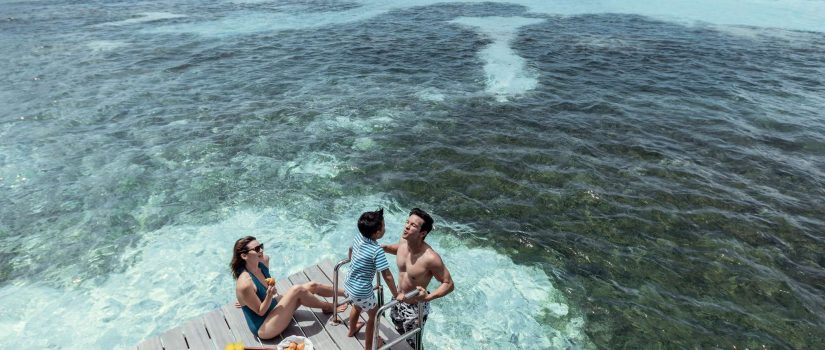 Club Med Kani, aux Maldives - Une famille mange et ris sur le bord d'un ponton.