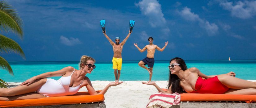 Club Med Kani, aux Maldives - Quatre personnes profitent de la plage sur des chaises longues. 