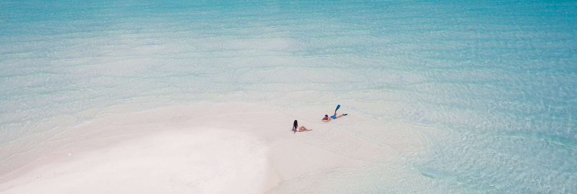 Club Med Villas de FInolhu, aux Maldives - Photo aérienne de deux personnes, seules sur la plage de la lagune