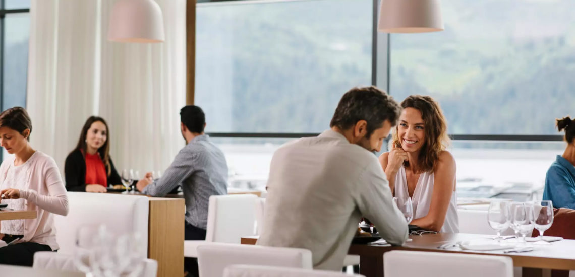 Club Med Samoëns, en France - Un couple est assis au Skyline bar, avec verres de vin à la main.